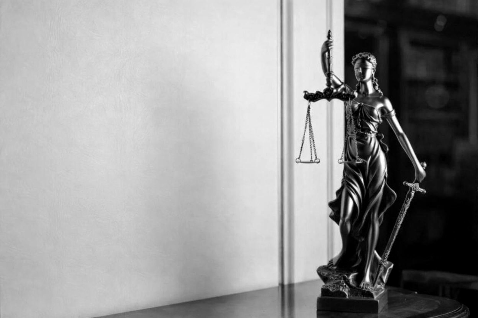 Statue of Lady Justice holding balanced scales in a law library